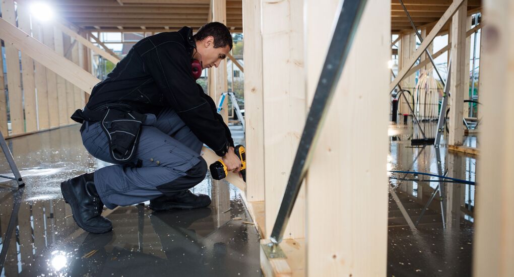 Zimmermann bohrt Holz auf der Baustelle